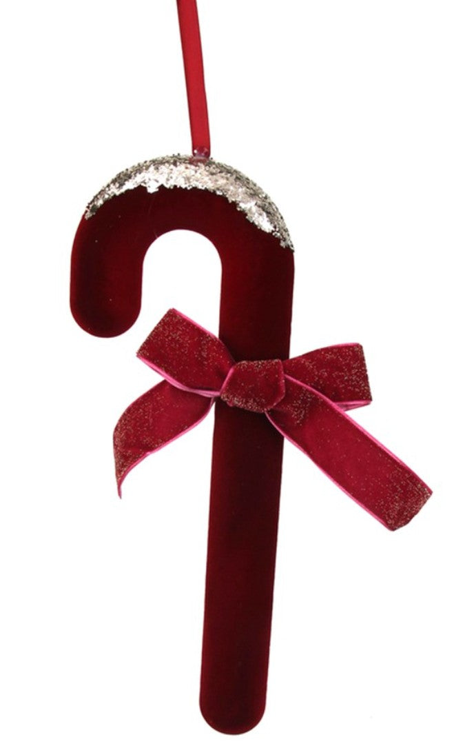 A red velvet candy cane Christmas ornament with a glittery silver top and a matching red velvet bow, hanging against a white background.