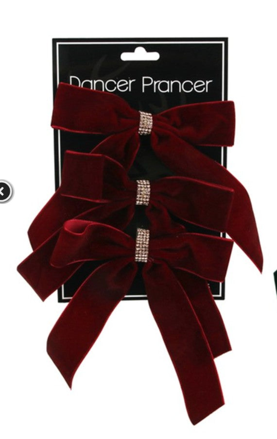 A pair of large deep burgundy velvet hair bows with rhinestone-embellished center bands, attached to a black retail display card labeled 'Dancer Prancer' on a white background.