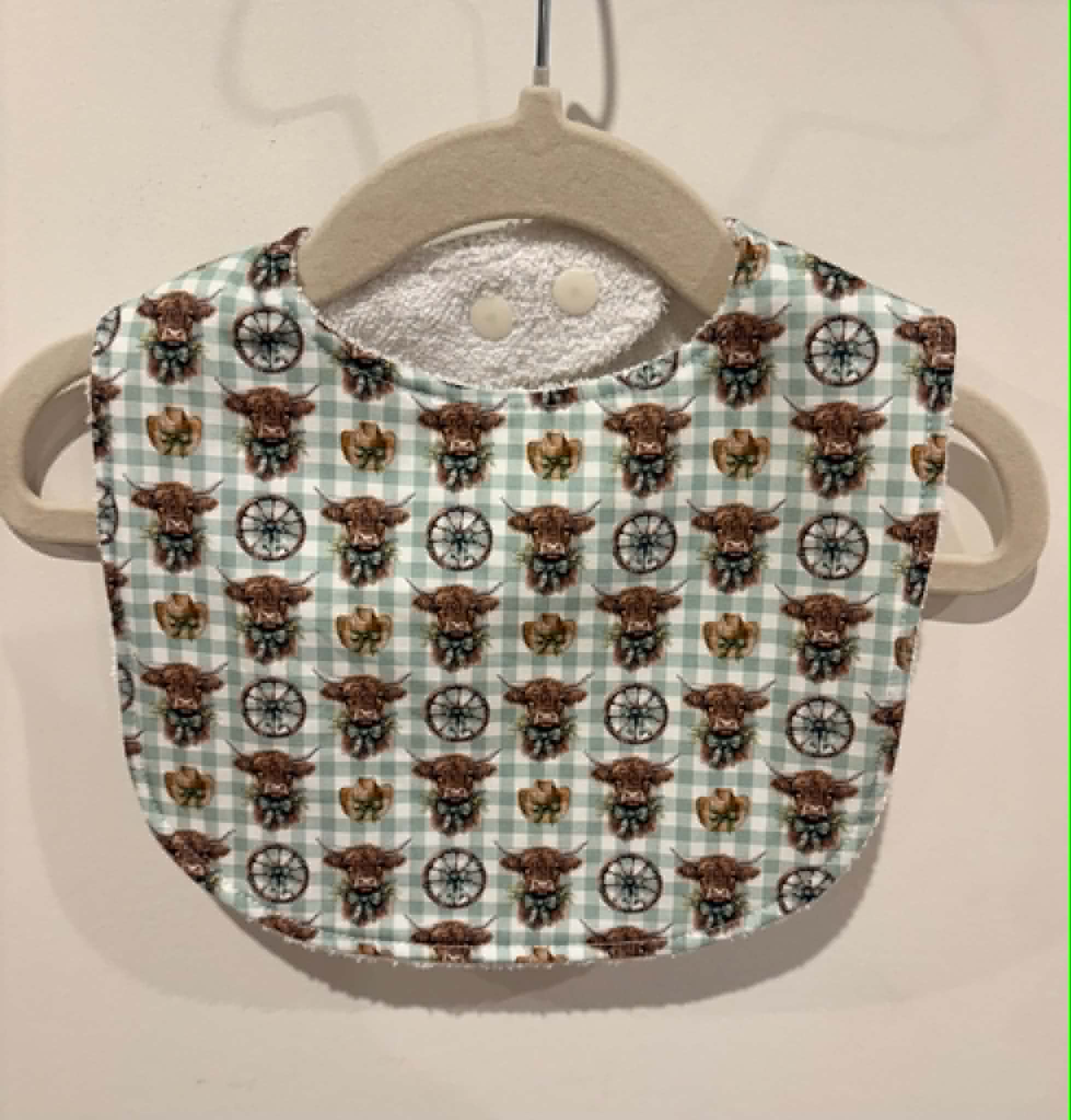 Green gingham baby bib with highland cows and cowboy details
