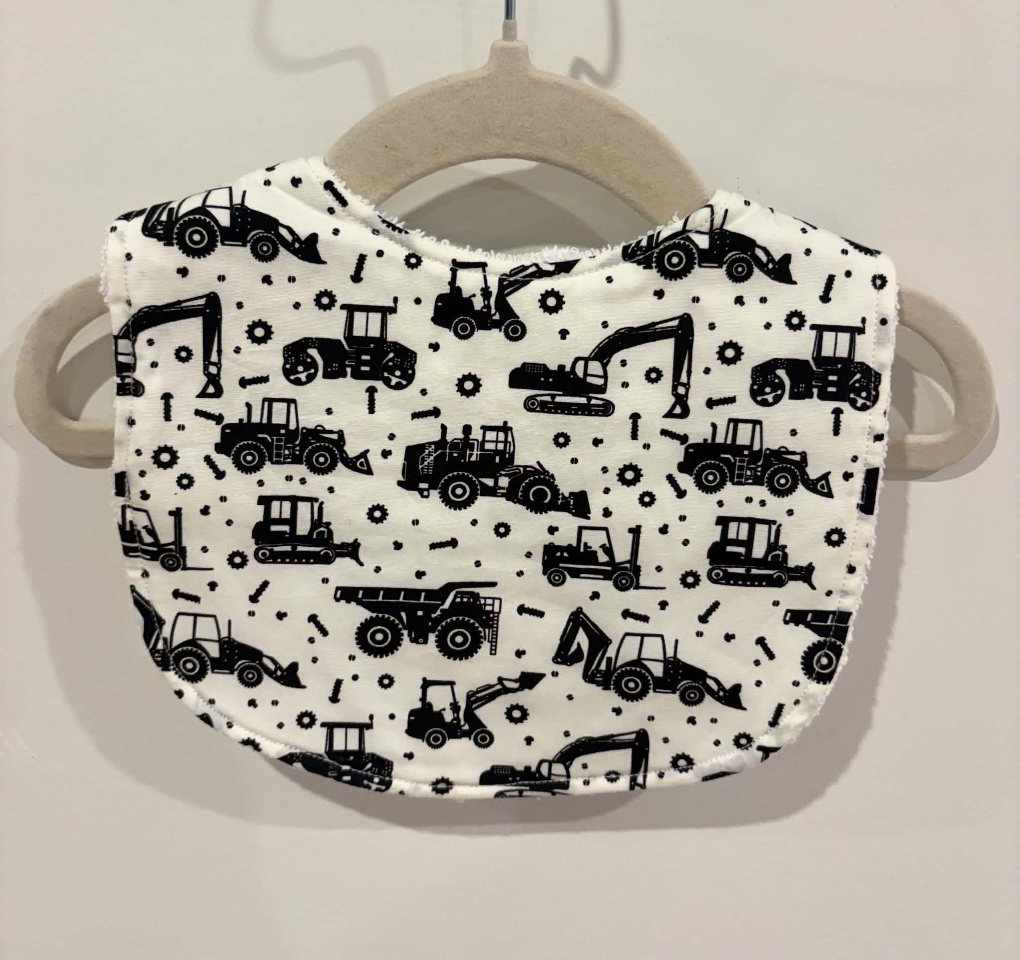 White baby bib featuring black construction vehicles print