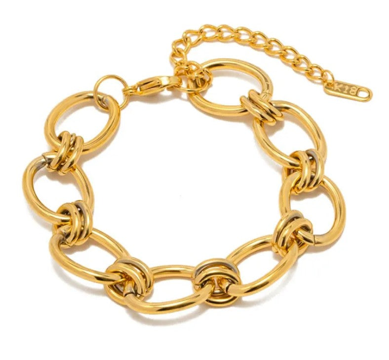 Gold stainless steel interlocking link bracelet with adjustable extension chain and lobster clasp.
