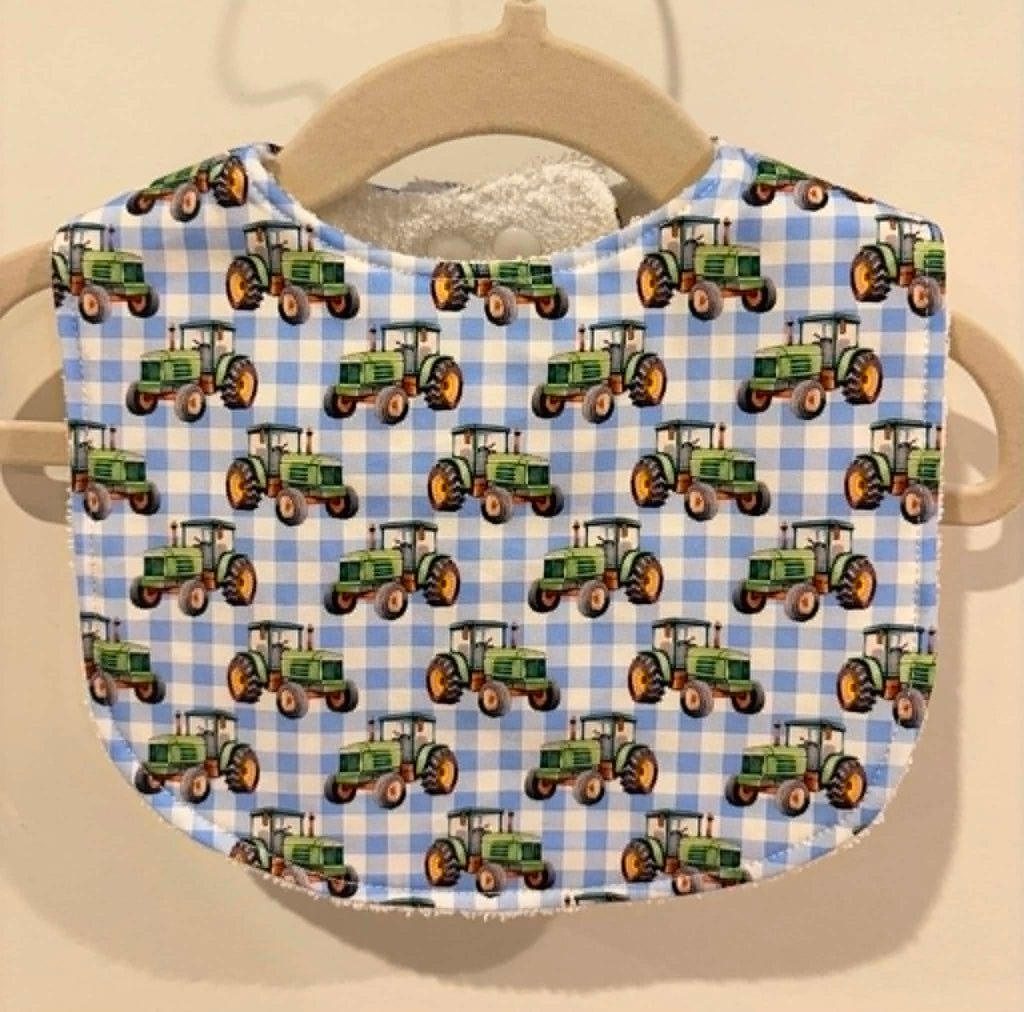 Baby bib with green tractors on blue gingham fabric