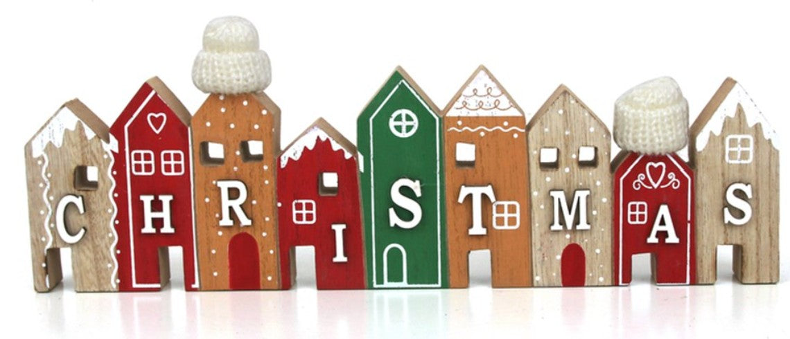 A set of small wooden house-shaped ornaments spelling out CHRISTMAS, each decorated with a different holiday color and white icing-style details, shown on a white background.
