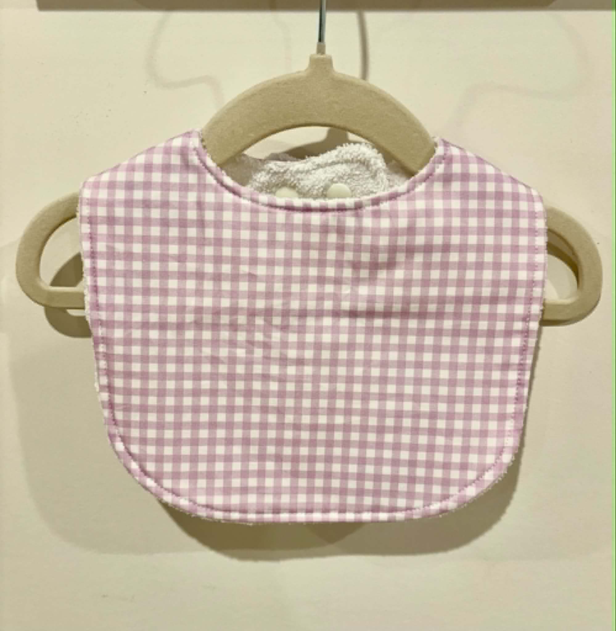 Pale mauve gingham baby bib on wooden hanger