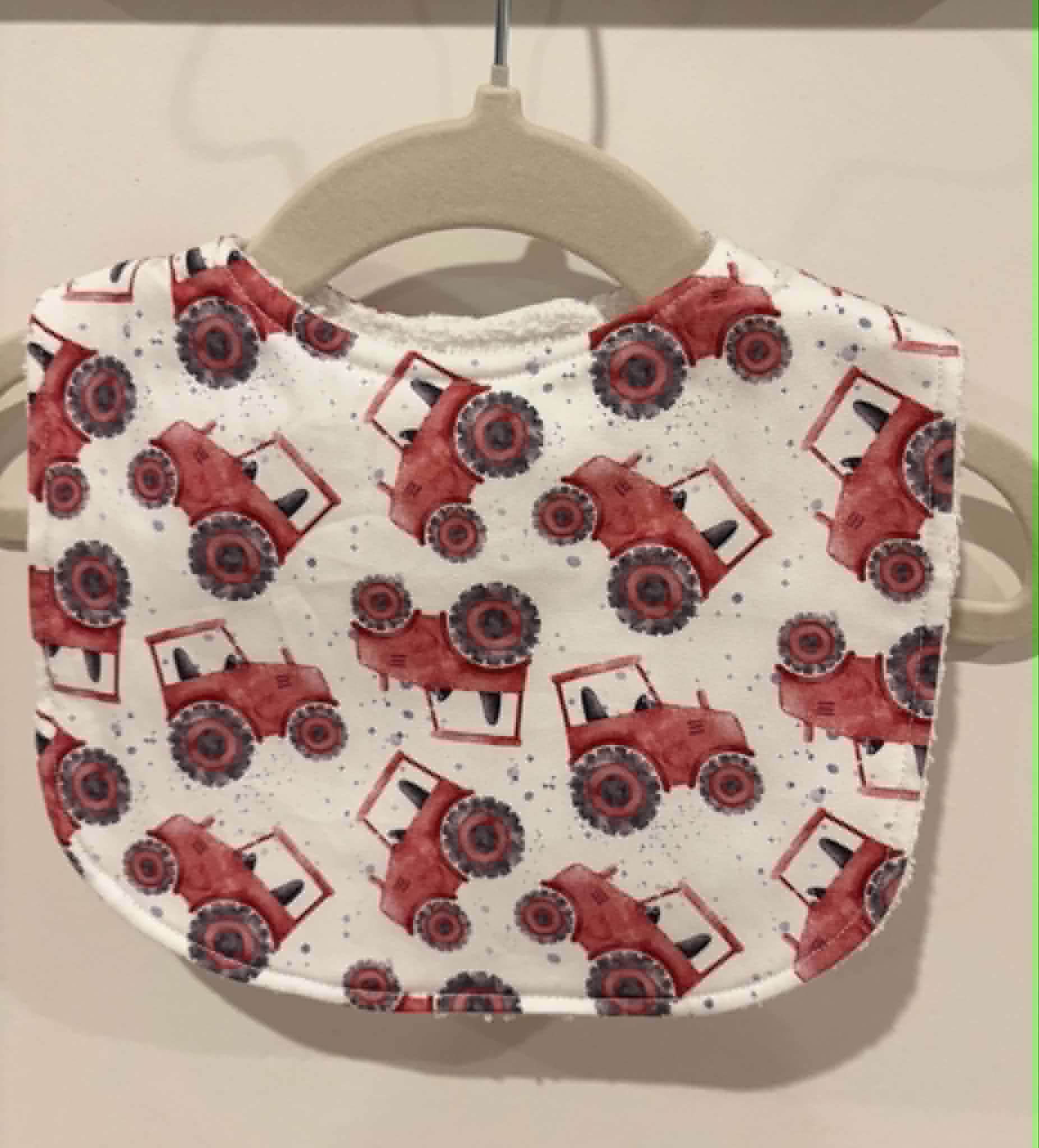 White baby bib with red tractor print