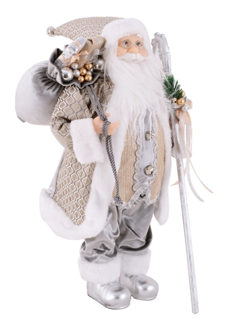 A decorative Santa Claus figurine wearing a textured beige and silver coat with white faux fur trim, carrying a sack on his shoulder and holding a silver staff, isolated on a white background.