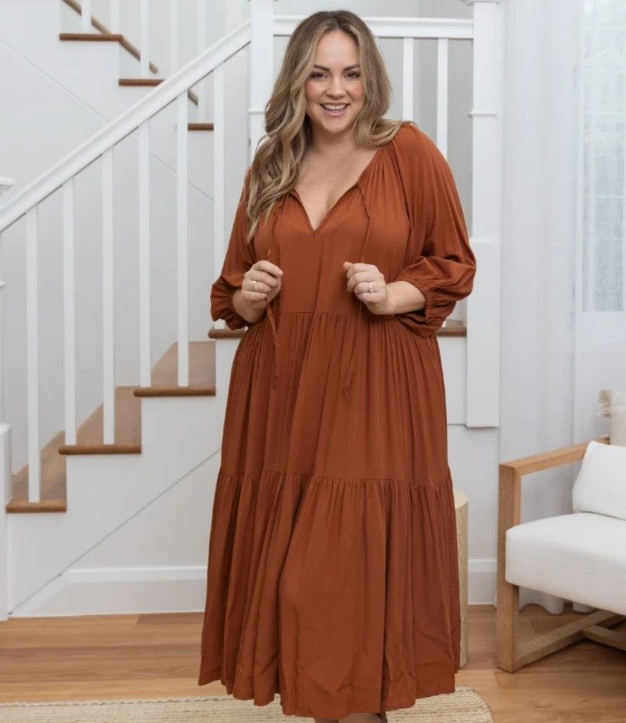 Woman wearing Jackson Midi Dress in tan with relaxed tiered silhouette, balloon sleeves and V-neckline