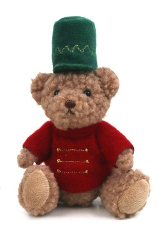 A plush teddy bear wearing a red jacket with gold buttons and a green hat, photographed against a plain white background.